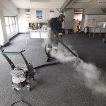 Office Carpet cleaning in progress. Technician working with high temperature steam, dirty water visible in the Steam Cleaner